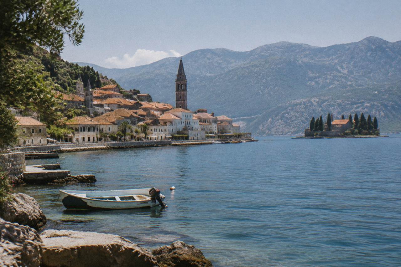 Stone houses and terracotta roofs of Perast rising above the calm blue water of the Bay of Kotor