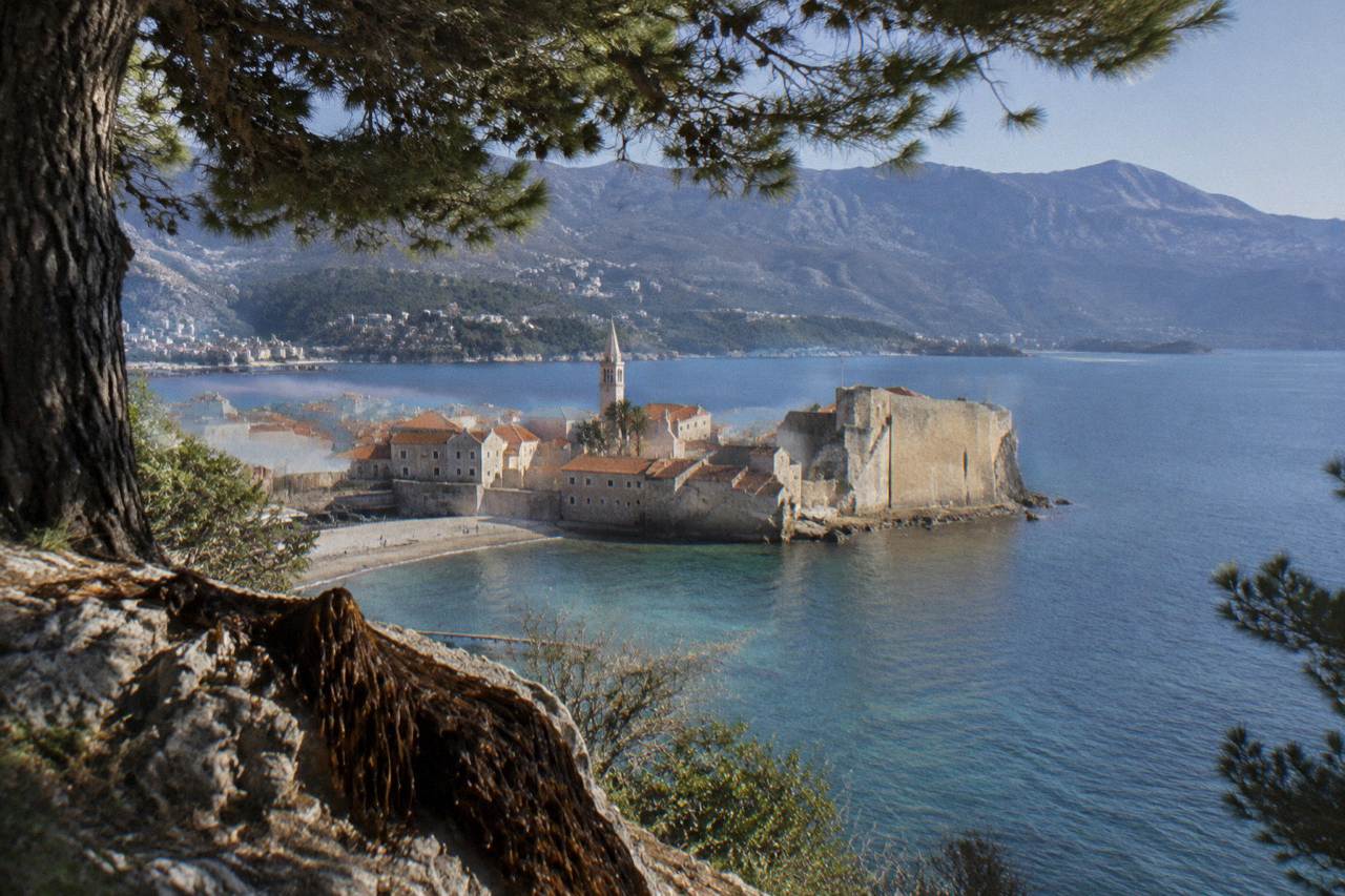 Walled old town on a blue Adriatic bay with mountains rising behind the water