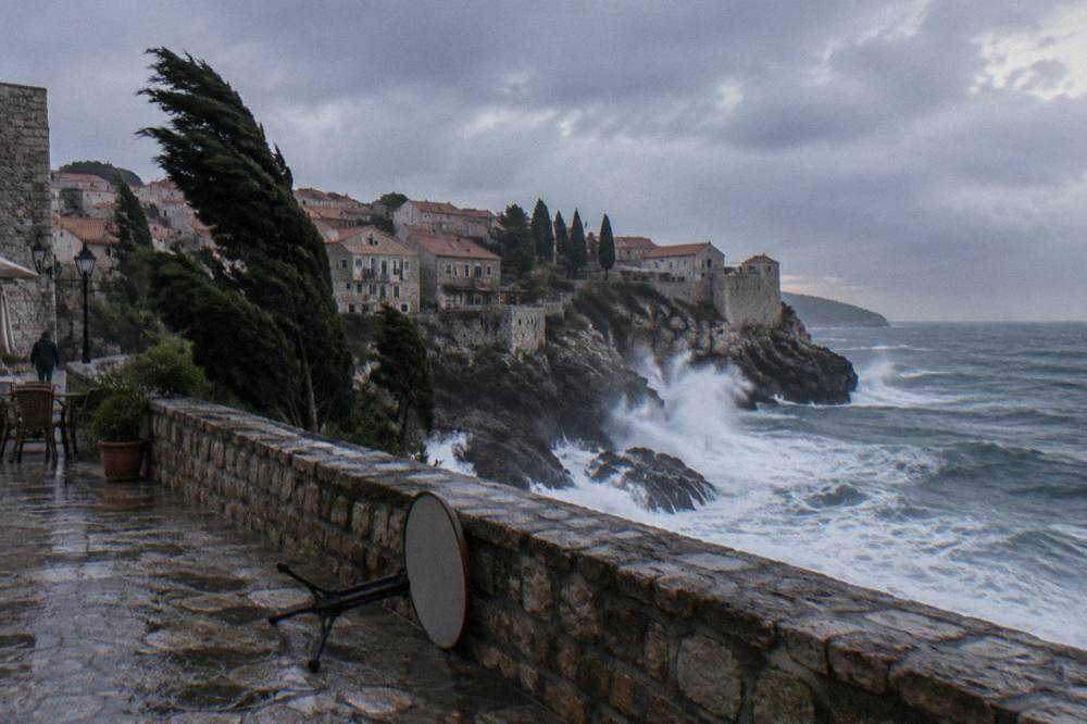 White waves breaking against rocky cliffs under a grey sky