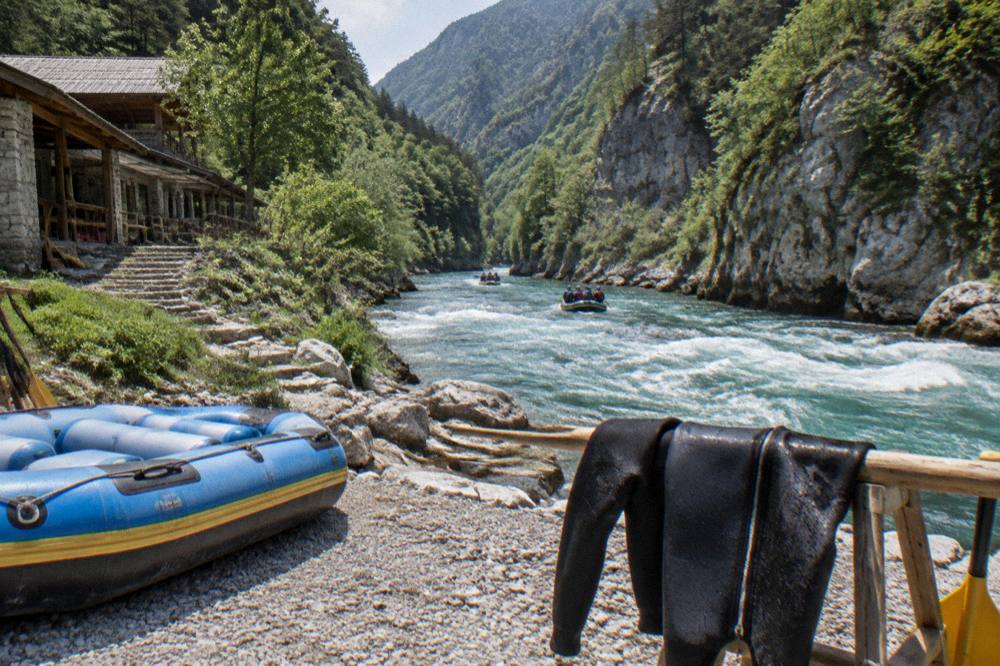 Turquoise river running through a deep forested canyon with rafts on the water