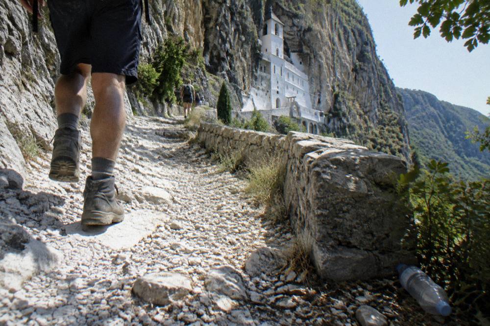 A stone path climbing toward white monastery buildings set high on a cliff
