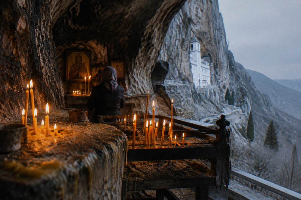 A small stone chapel interior with candle light on old walls