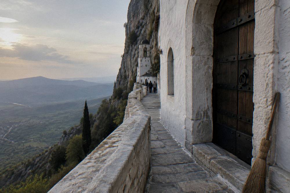 A wooden monastery door set into white stone walls above a valley