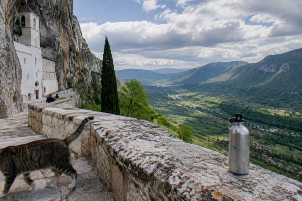 Rolling green hills and a wide valley seen from a high stone terrace