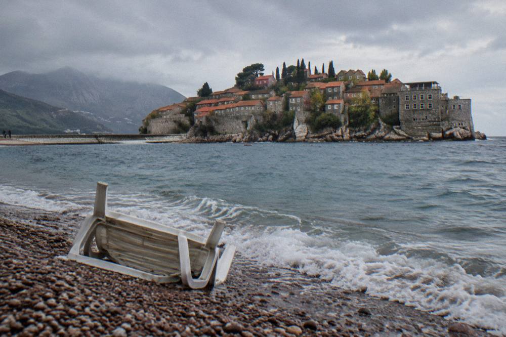 Stone houses of Sveti Stefan village clustered on the islet seen across the water from the mainland viewpoint
