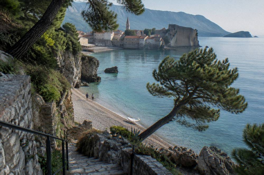 Mogren beach cove with clear water and wooded cliffs near Budva