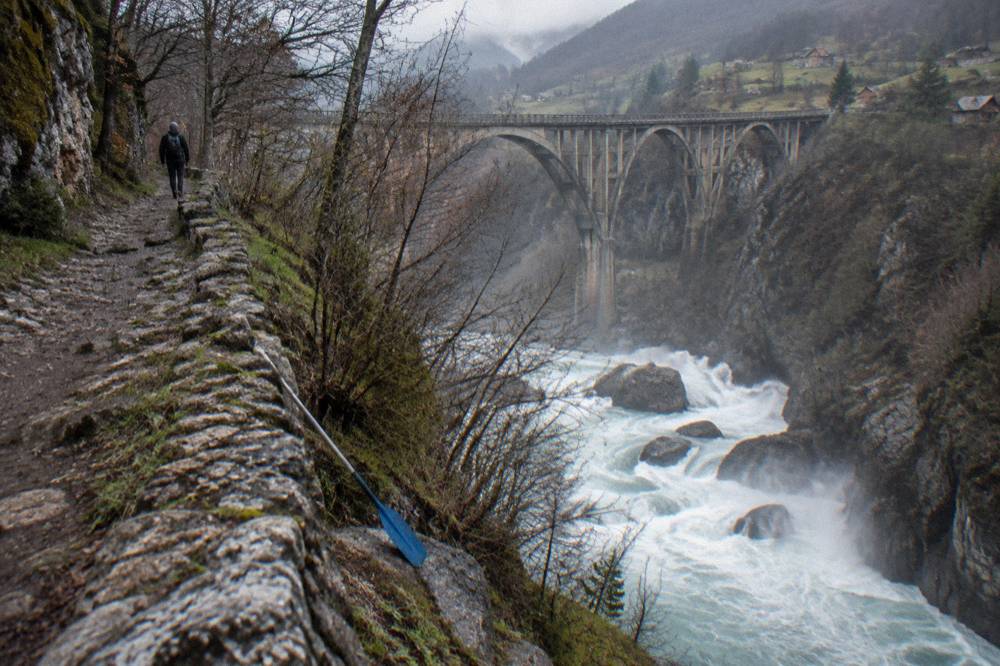 Fast spring rapids with white water pouring over boulders in a deep canyon