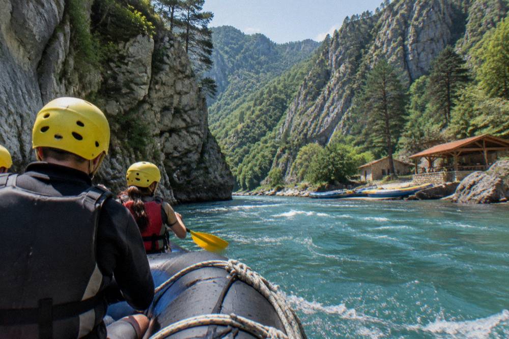 Raft floating through a deep river canyon with forested cliffs on both sides